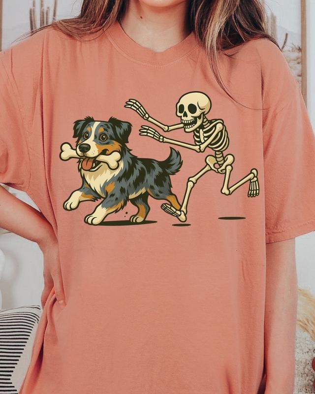 Funny Skeleton Chasing Blue Merle Aussie Dog Halloween T-Shirt | Spooky Graphic Tee Comfort Colors Style Unisex Relaxed Fit 100% Ring-Spun Cotton Honduras Made