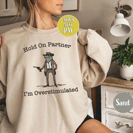 [SALE UP TO 45%] Hold On Partner I'm Overstimulated Cowb0y Fr0g Funny Meme Sweatshirt, Funny Fr0g Western Cowb0y Gift Cotton Unisex Womenswear